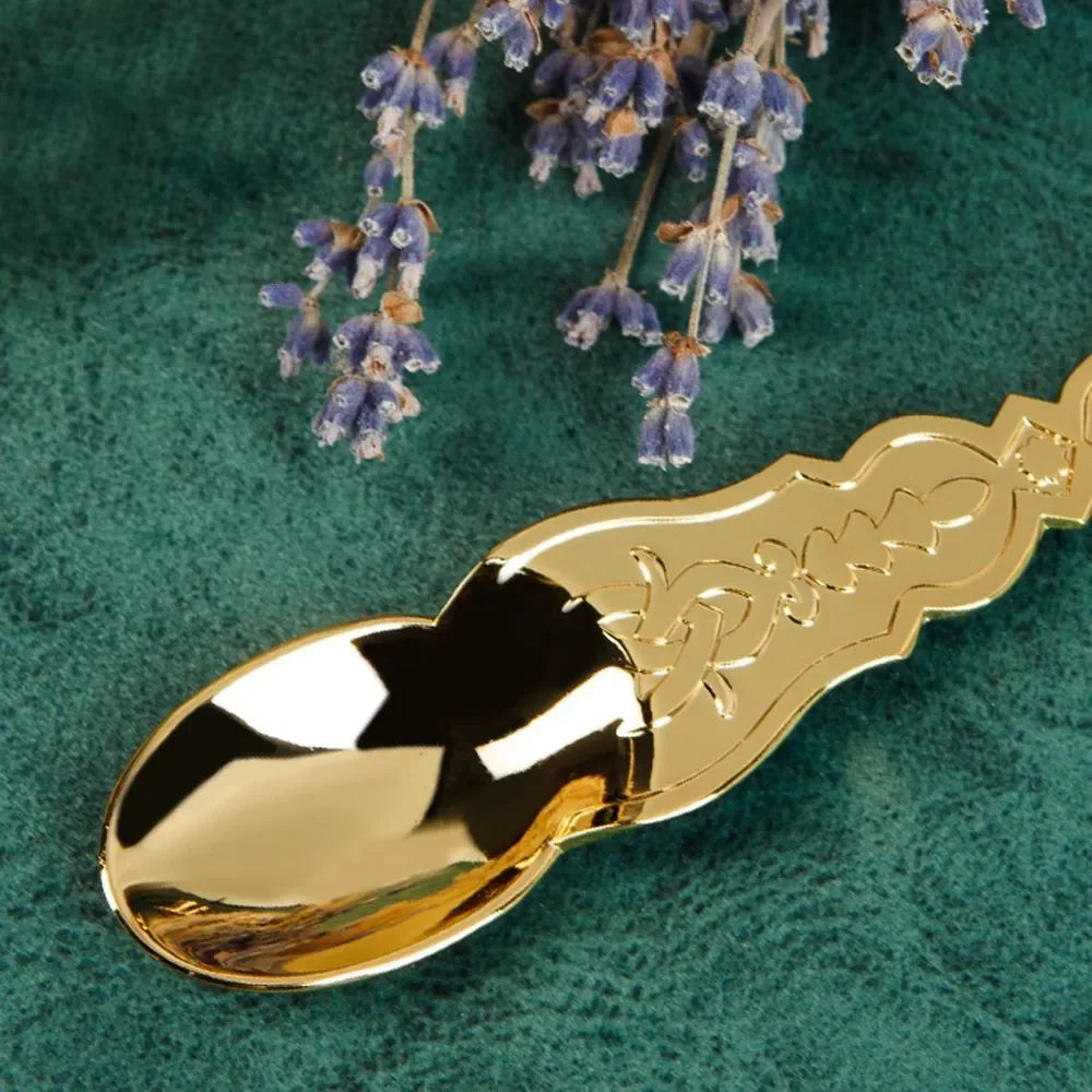 Gold decorative spoon on a green surface with lavender flowers
