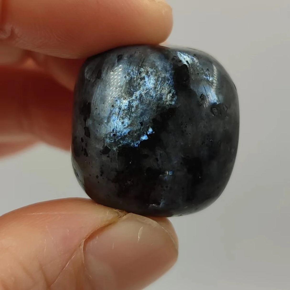 Person holding a dark blue stone with a white interior against a plain background