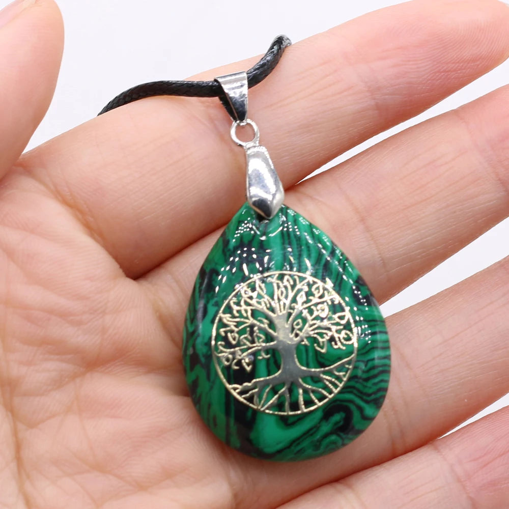 Green marbled pendant with silver tree design held in a hand against a white background