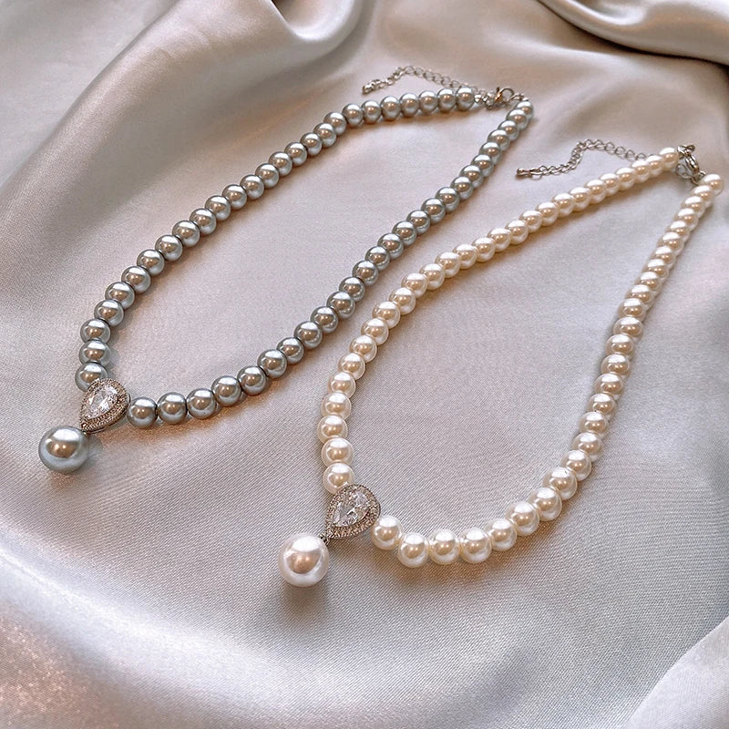 Two pearl necklaces on a soft, light-colored fabric background