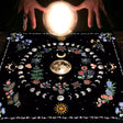 Crystal ball held above a black cloth with astrological designs and plants.
