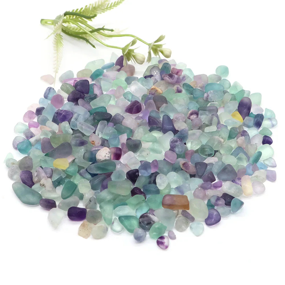 Hand holding a small pile of multicolored gemstones