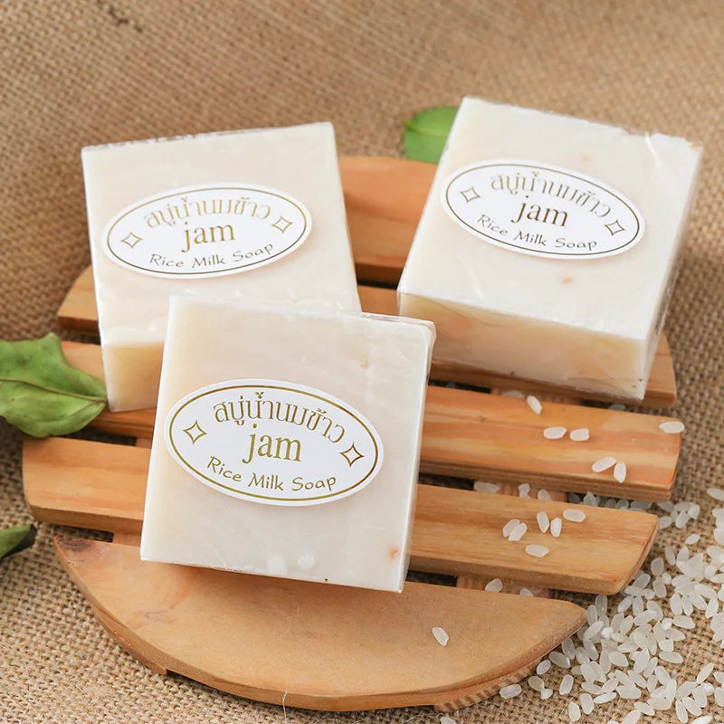 Three bars of rice milk soap on a wooden board with a burlap background