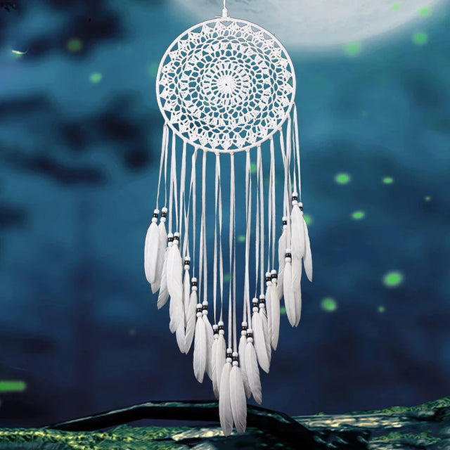 White dreamcatcher with feathers against a night sky with stars
