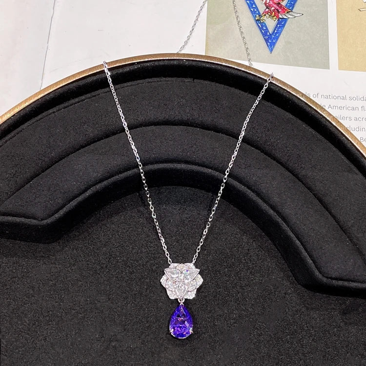 Diamond necklace with purple gemstone on a black display stand with 'CUMEE' branding.