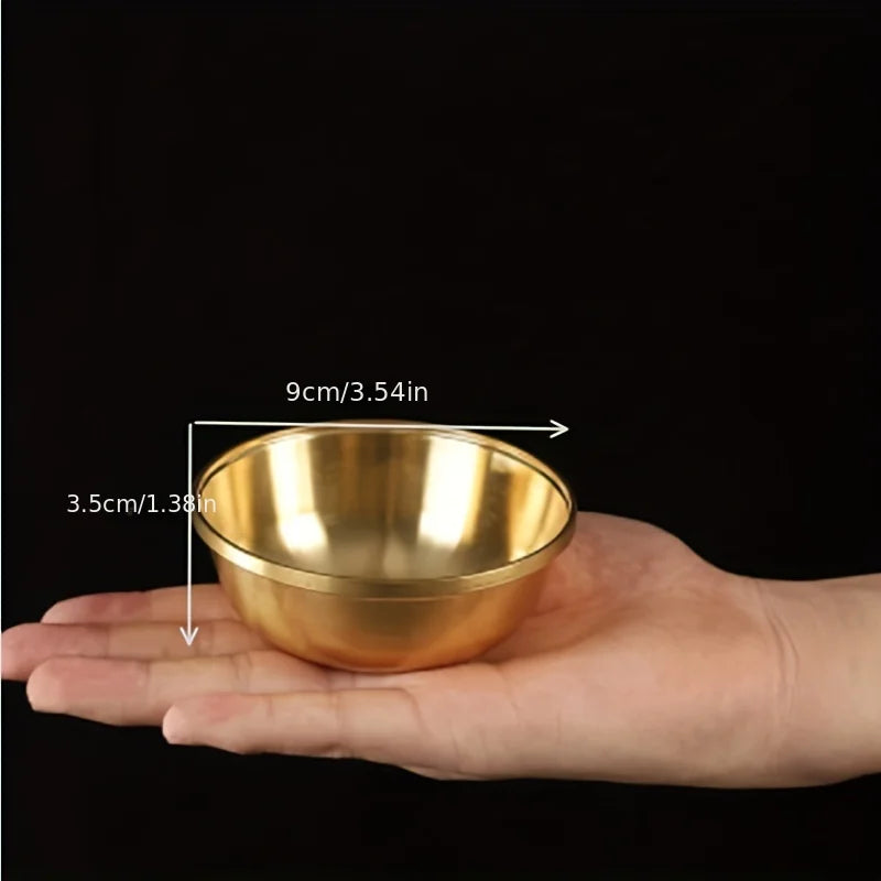 Gold bowl held in a hand with measurements indicated on a black background