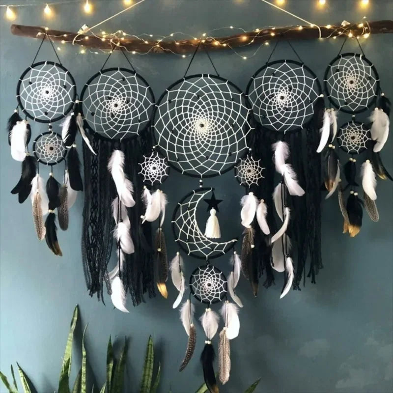 Set of dreamcatchers with feathers hanging against a wall with string lights.