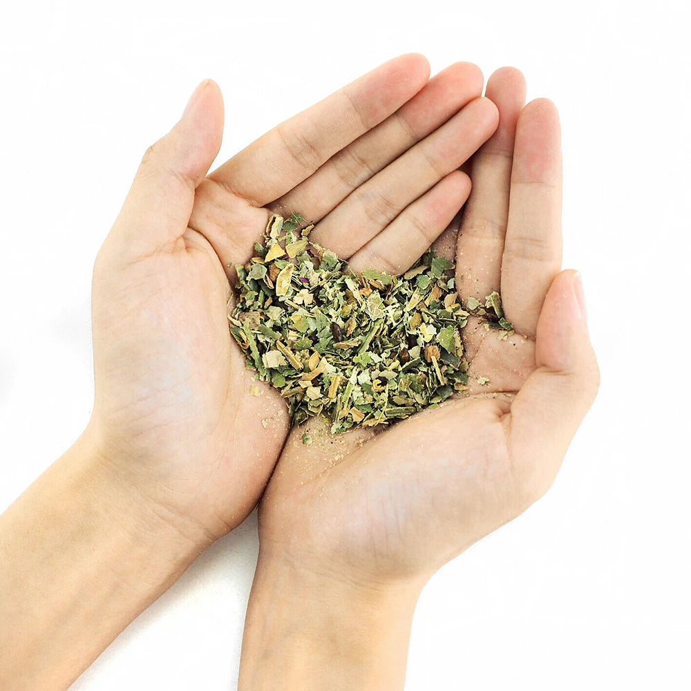 Hands holding a small amount of dried herbs on a white background