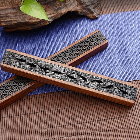 Wooden incense holders with black wave pattern on a textured surface