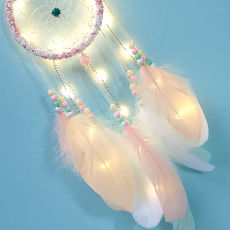 Decorative dreamcatcher with feathers and lights on a light blue background