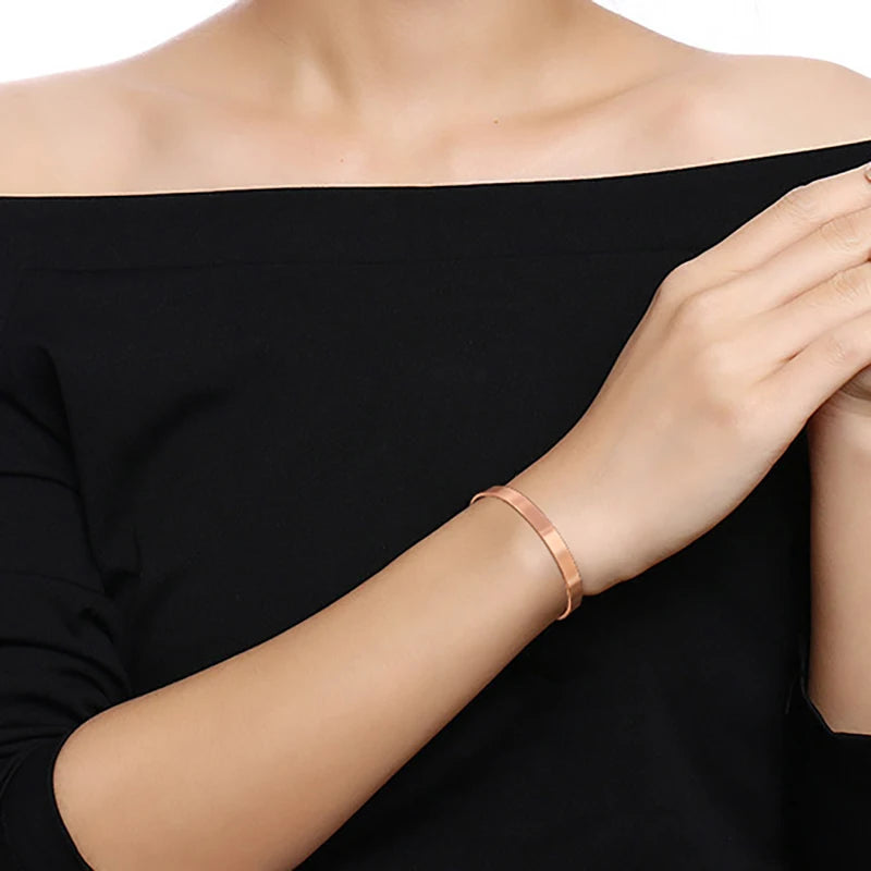 Rose gold bracelet on a person wearing a black off-shoulder top.