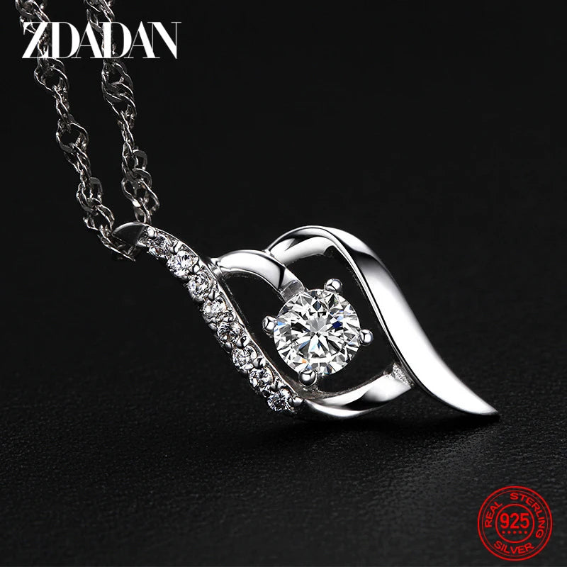 Silver necklace with a heart-shaped pendant featuring a central gemstone on a black background, branded 'ZDADAN'.