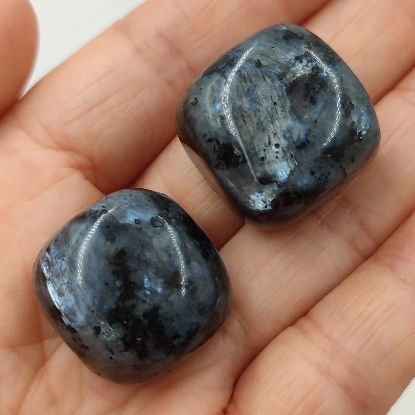 Two dark blue stones held in a hand against a neutral background