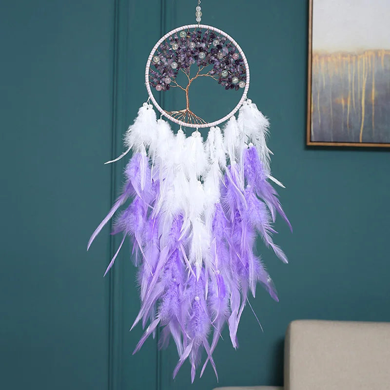 Decorative dreamcatcher with purple and white feathers hanging against a teal wall.