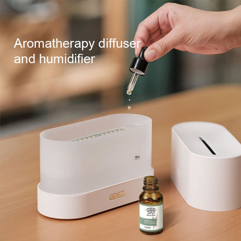 Aromatherapy diffuser and humidifier with a hand dropping oil into it on a wooden surface.