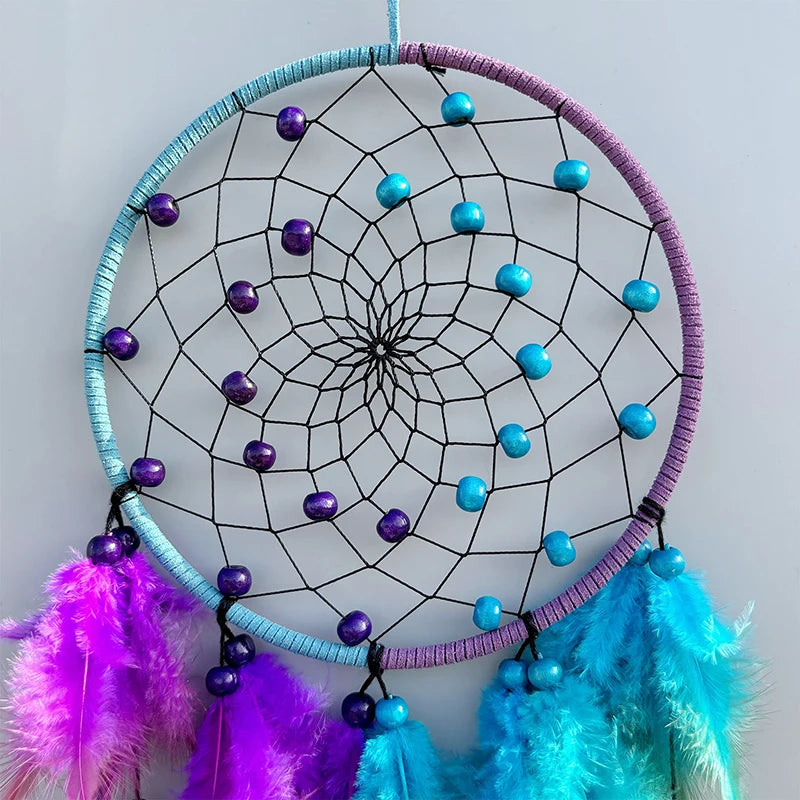 Dreamcatcher with purple and blue feathers on a light gray background