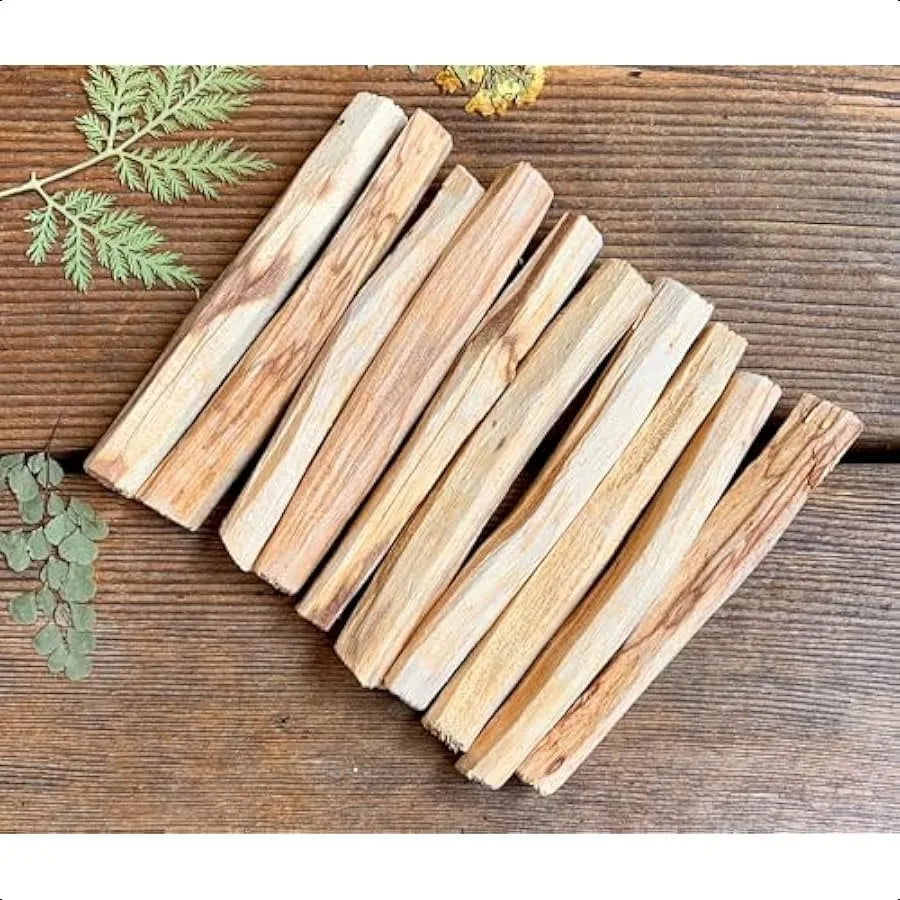 Stack of wooden planks on a wooden surface with green leaves.