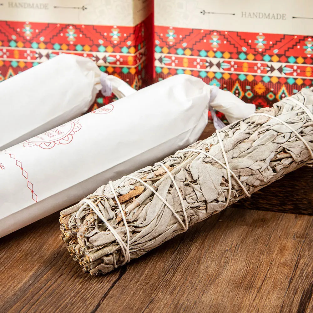 White sage smudge stick on a wooden surface with colorful packaging in the background