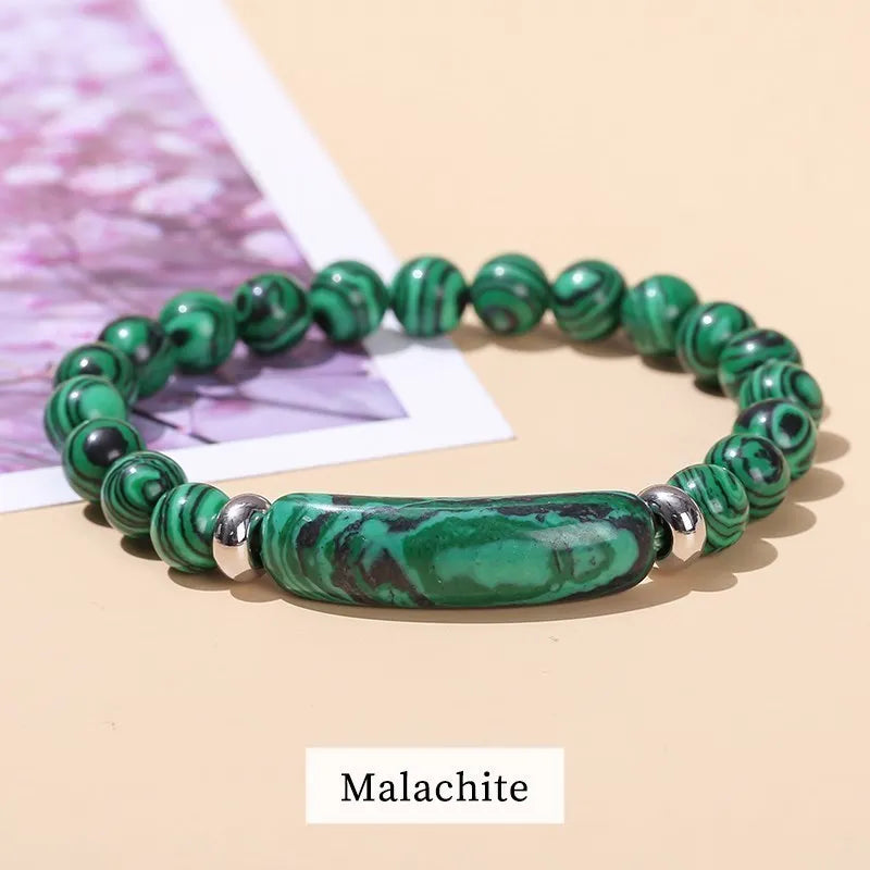 Green malachite beaded bracelet on a beige surface with 'Malachite' label.