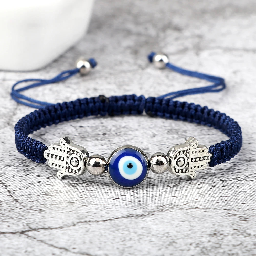 Navy blue bracelet with Hamsa hand and evil eye charm on a light wooden surface
