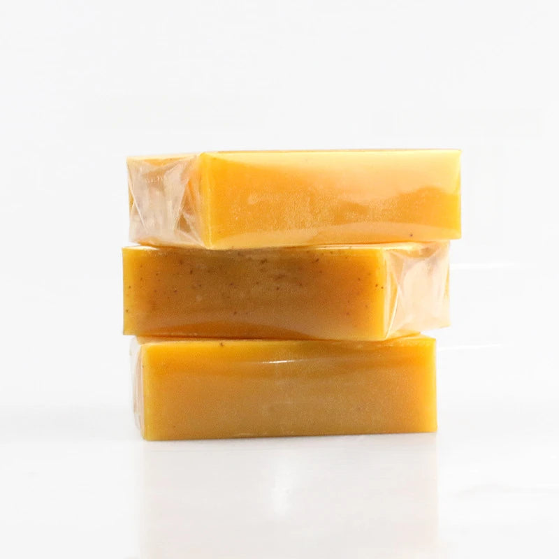 Three bars of yellow soap stacked on a white background