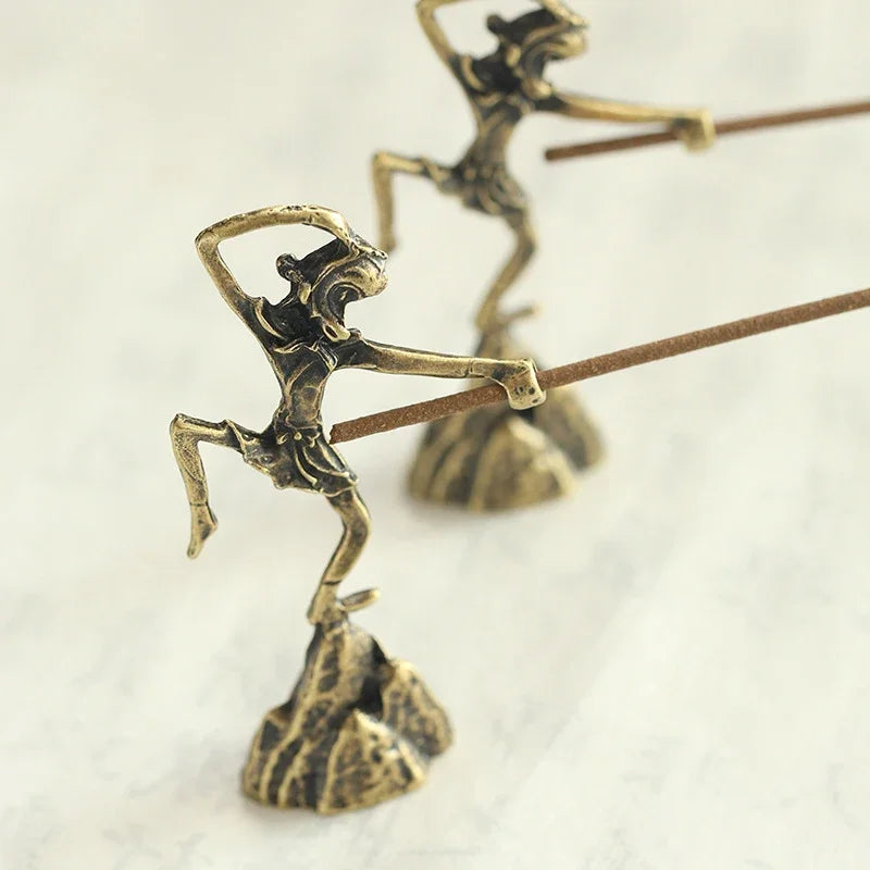 Bronze sculptures of figures on a rock with a white background