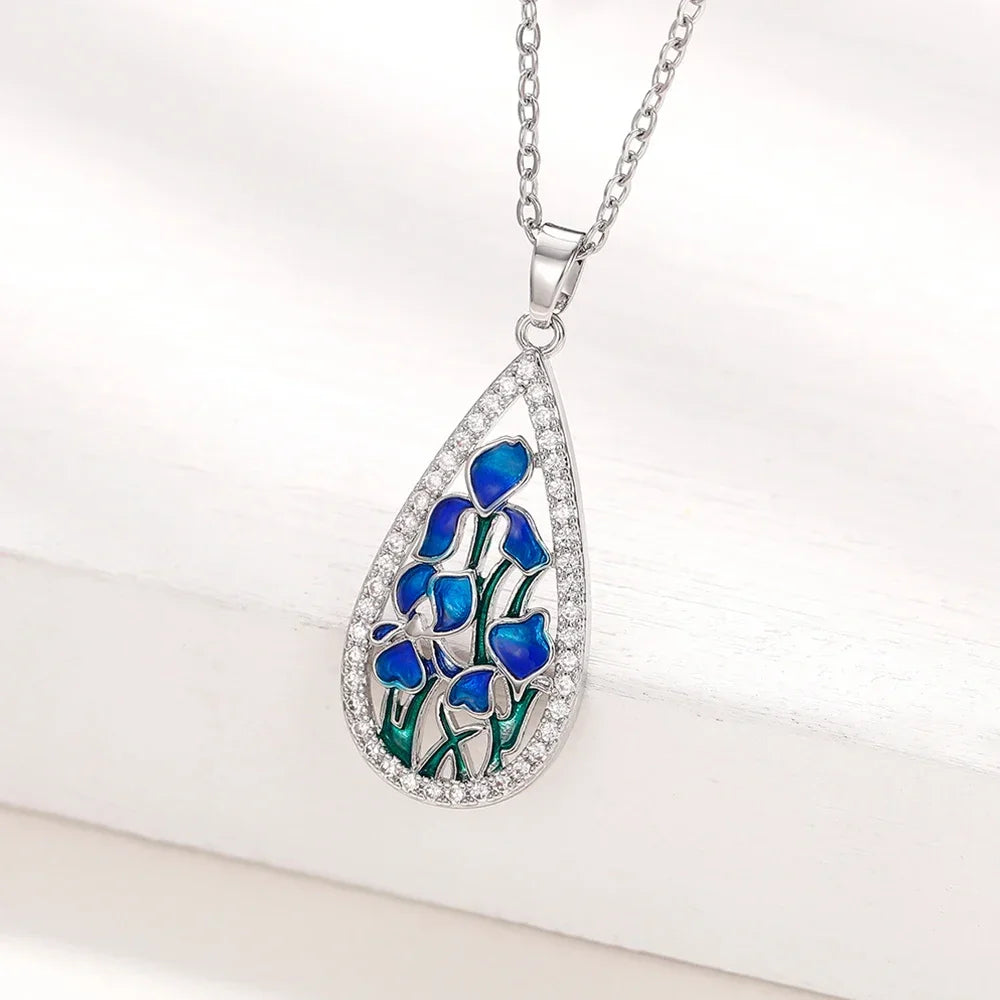 Teardrop-shaped pendant with blue floral design and clear stones on a white background