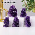 Purple crystal formations on a white surface with a blurred plant and gold decorative item in the background.