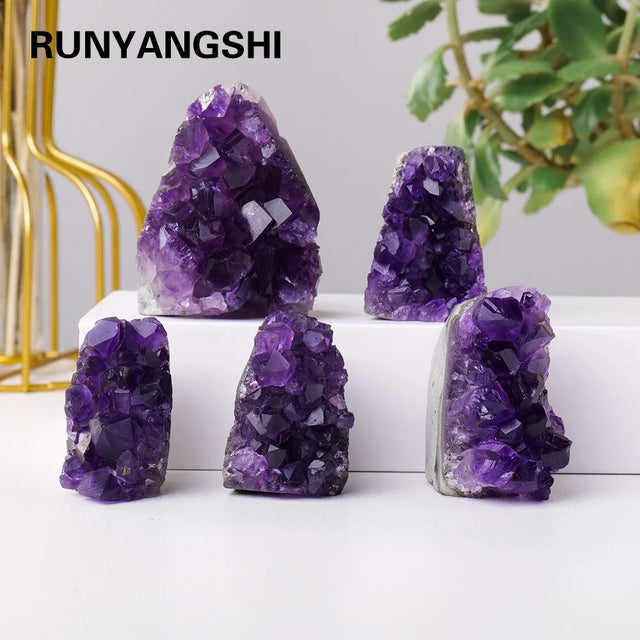 Purple crystal formations on a white surface with a blurred plant and gold decorative item in the background.
