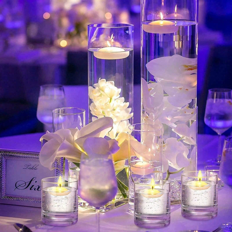 Decorative table setting with floating candles and flowers in clear containers.
