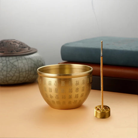 Brass incense burner with incense stick on a wooden surface