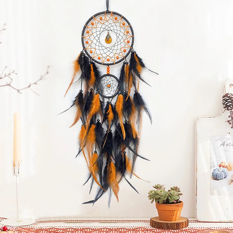 Black and orange dreamcatcher hanging on a white wall with decor elements below.