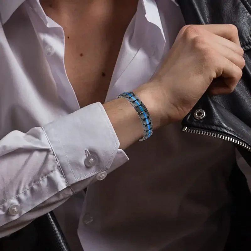 Person wearing a white shirt with rolled-up sleeves, holding a black leather jacket, and wearing a blue beaded bracelet.