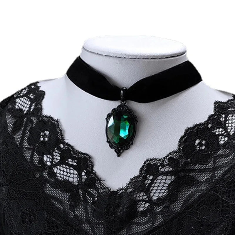 Black velvet choker with a green gemstone on a mannequin against a white background