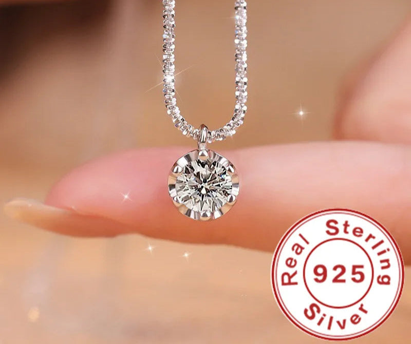 Silver necklace with a round pendant held by fingers, Andara brand visible, 'Real Sterling 925' stamp.