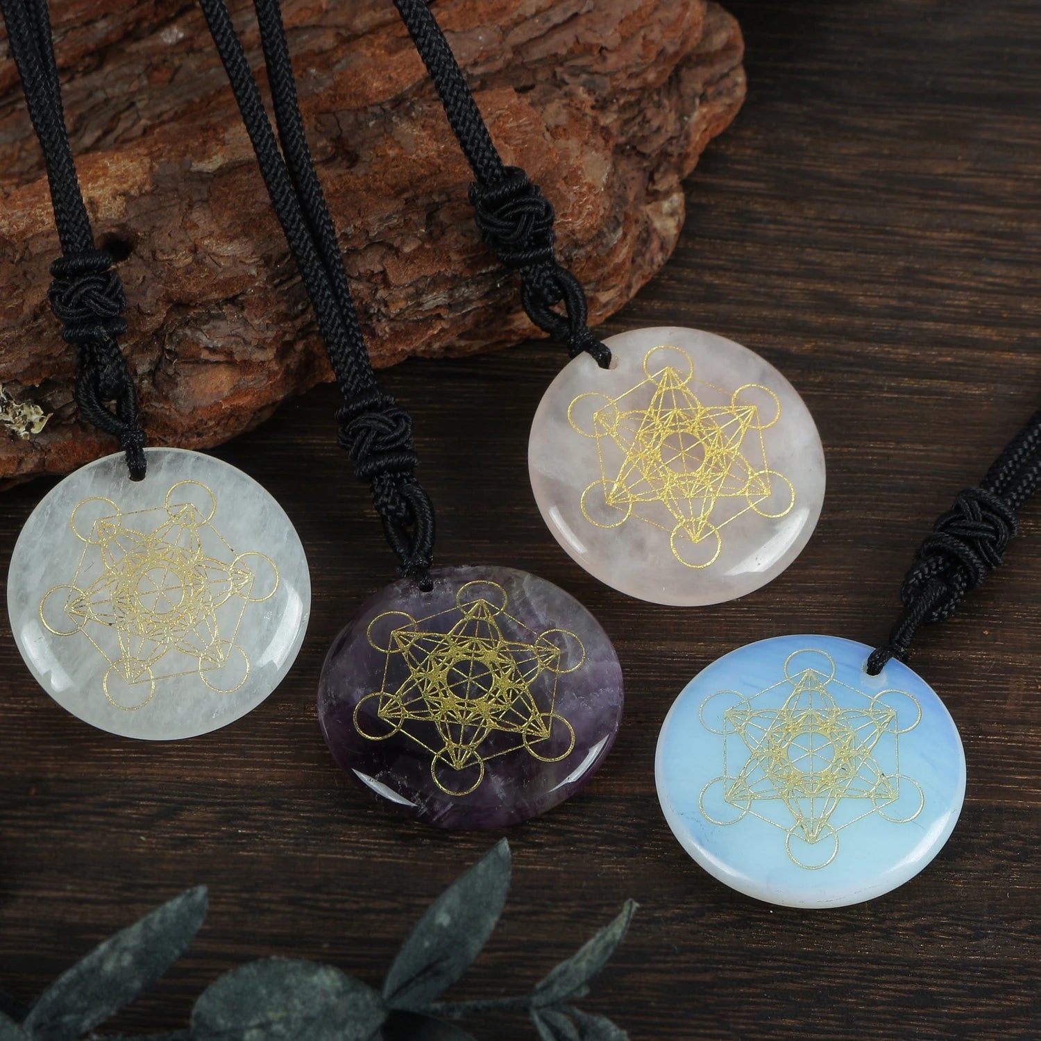 Four stone pendants with geometric designs on a wooden surface