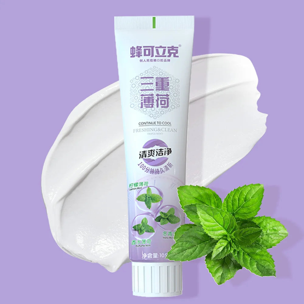 Tube of 'Honeysuckle' toothpaste with mint leaves on a purple background