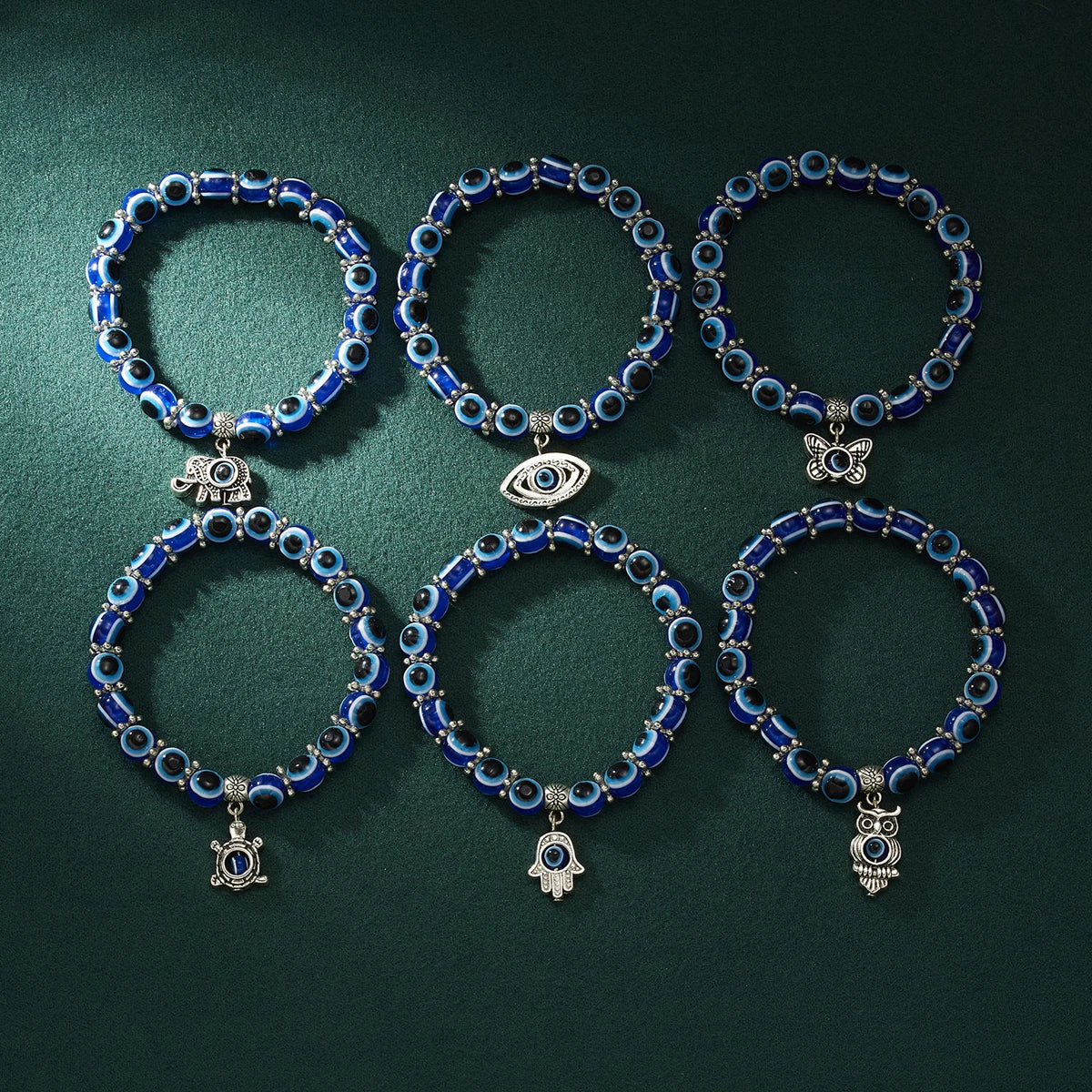 Set of blue beaded bracelets with various charms on a dark green background