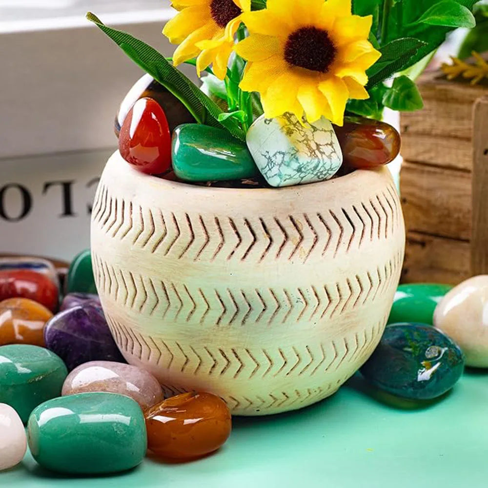 Decorative pot with sunflowers and colorful stones on a light green surface