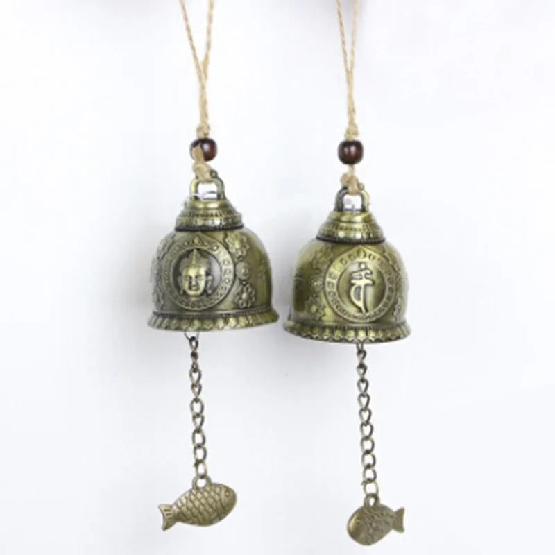 Two brass bells with fish charms on a white background