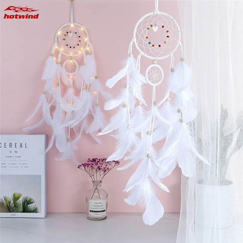 White dreamcatcher with feathers and lights on a pink wall