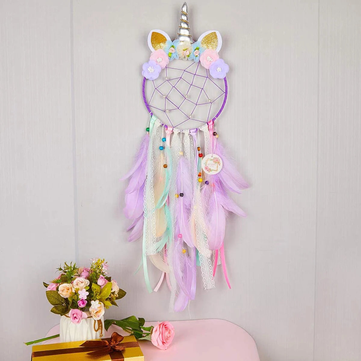 Unicorn-themed dreamcatcher with colorful feathers on a light gray background