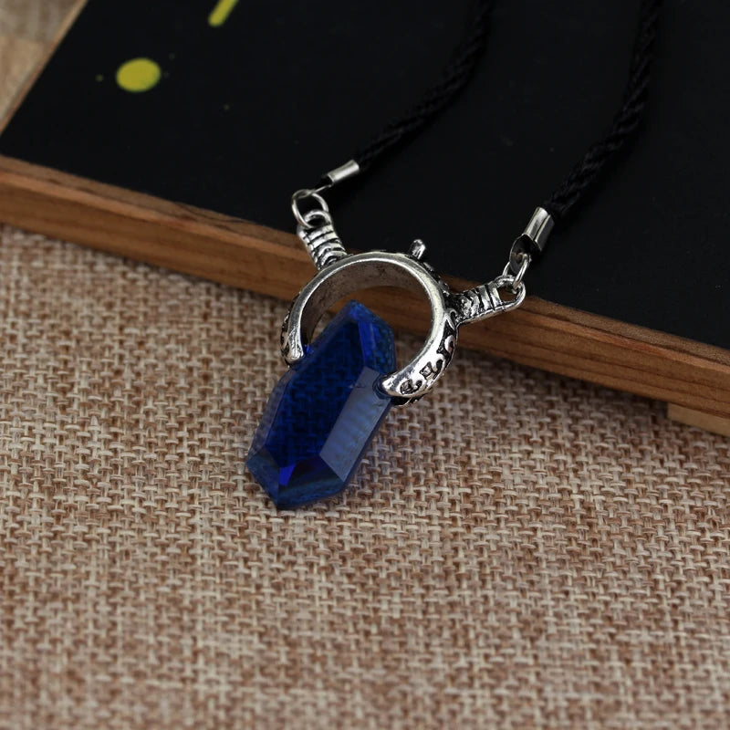 Silver pendant with blue stone on a black cord against a textured brown surface