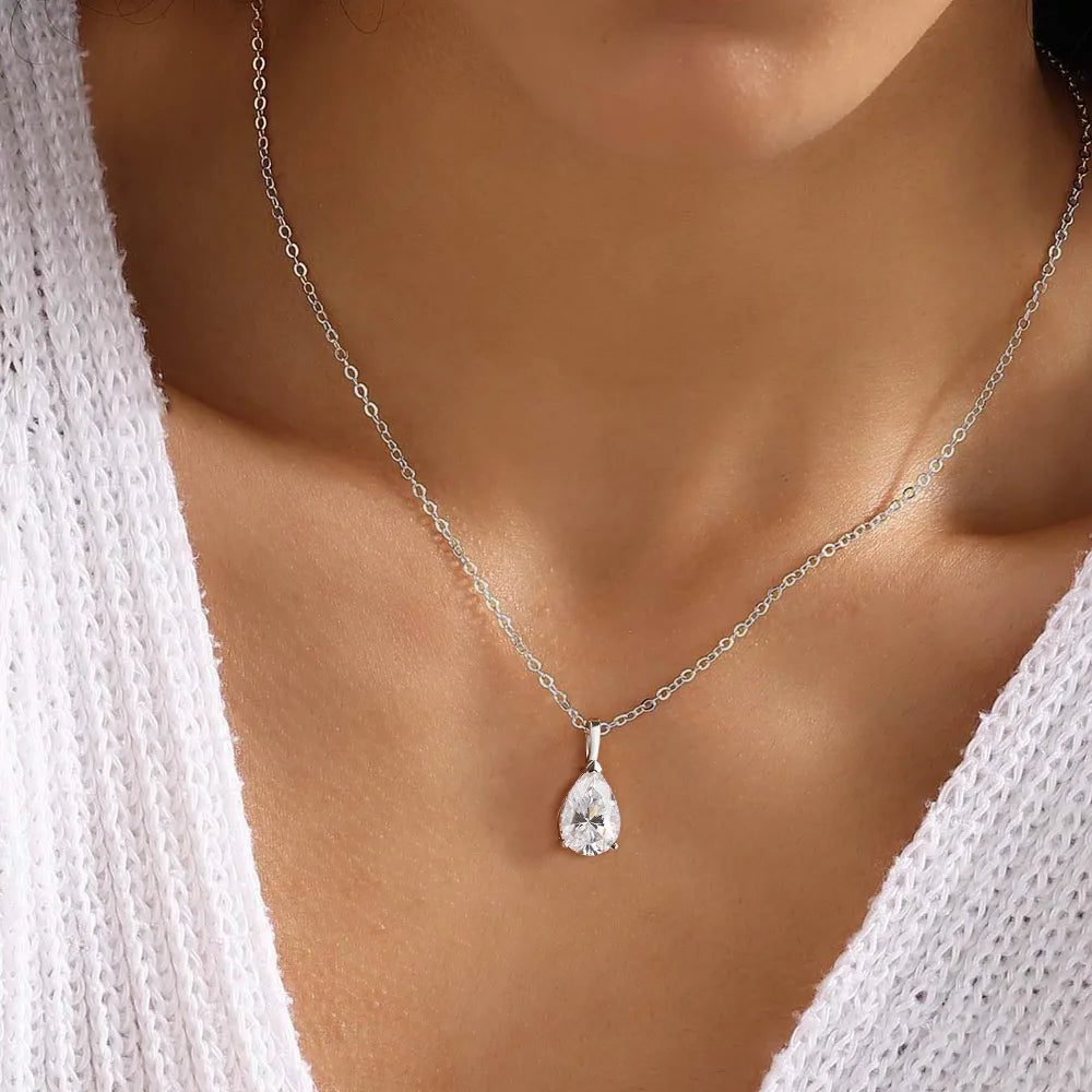 Silver necklace with a teardrop-shaped pendant on a person wearing a white top.