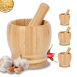Wooden mortar and pestle with garlic and red peppers on a white background