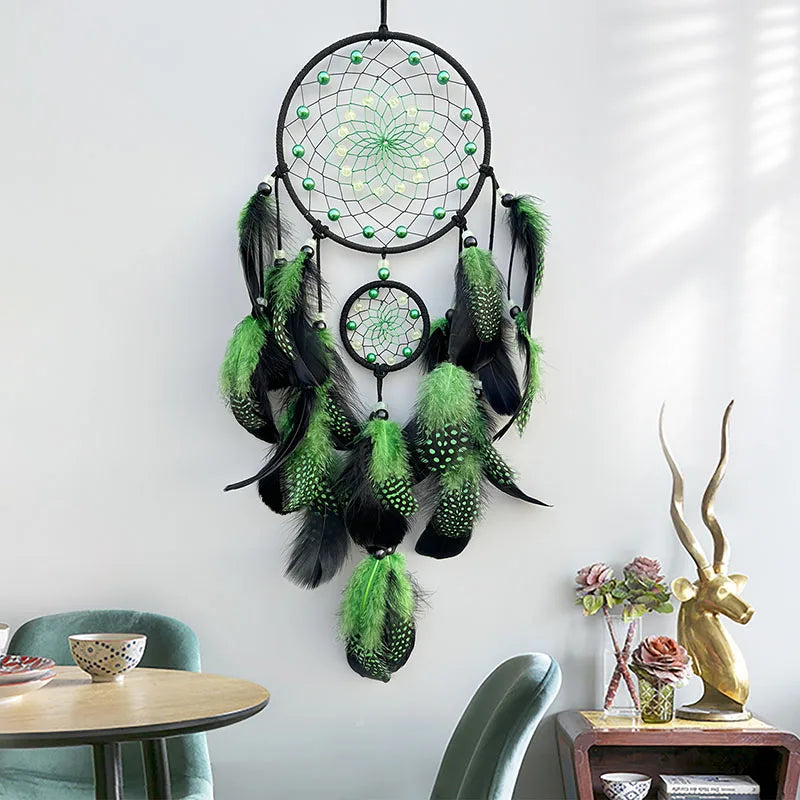 Green and black dreamcatcher hanging on a wall with decorative elements below.