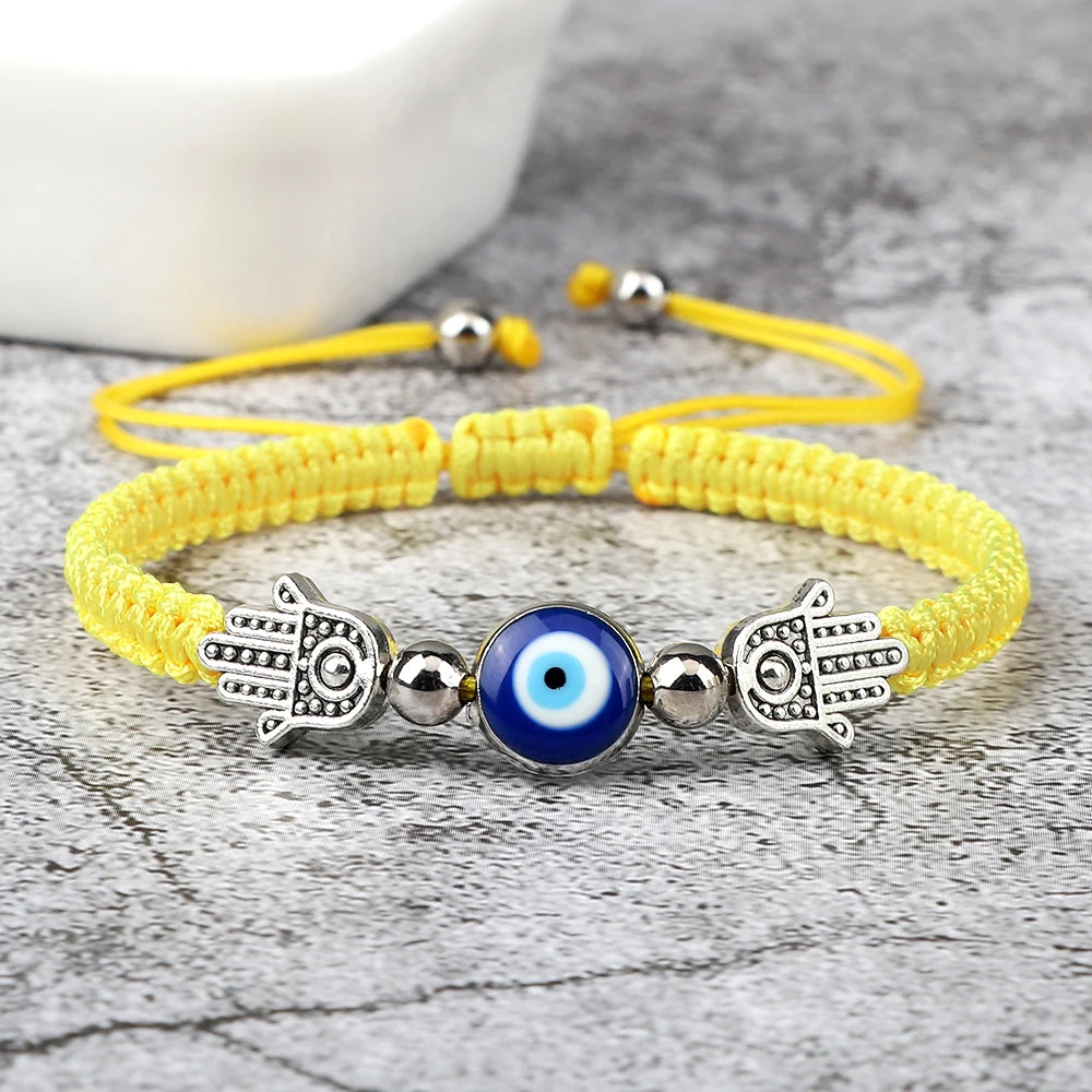 Yellow bracelet with Hamsa hand and blue evil eye bead on a gray surface