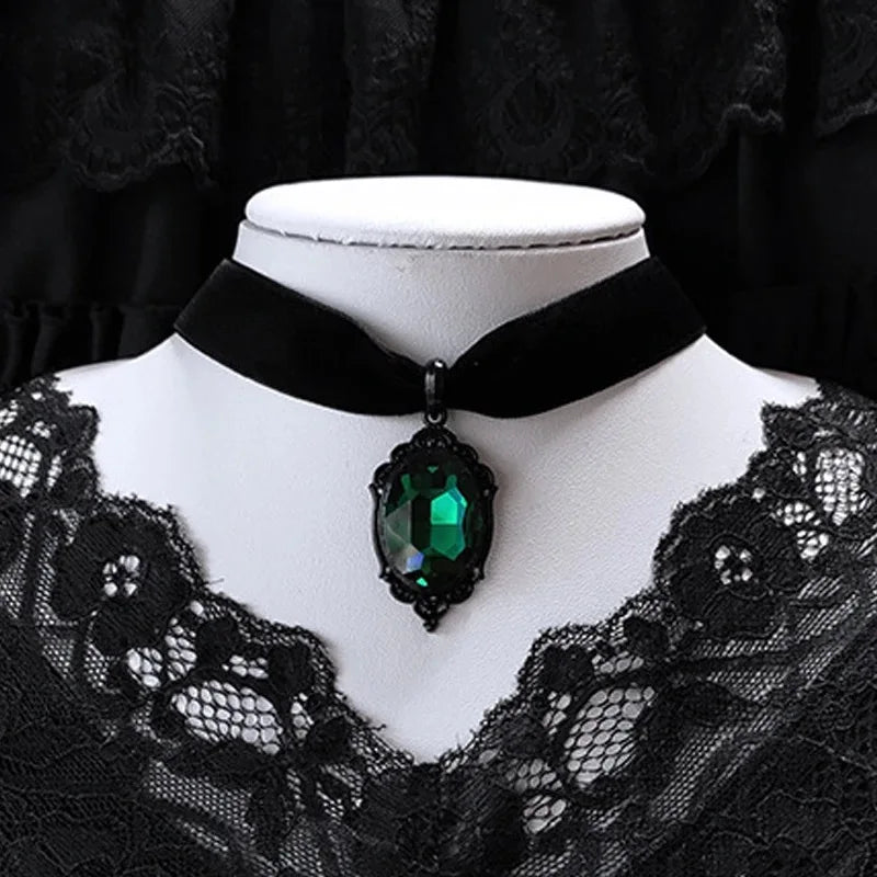 Black velvet choker with a green gemstone on a mannequin against a black background
