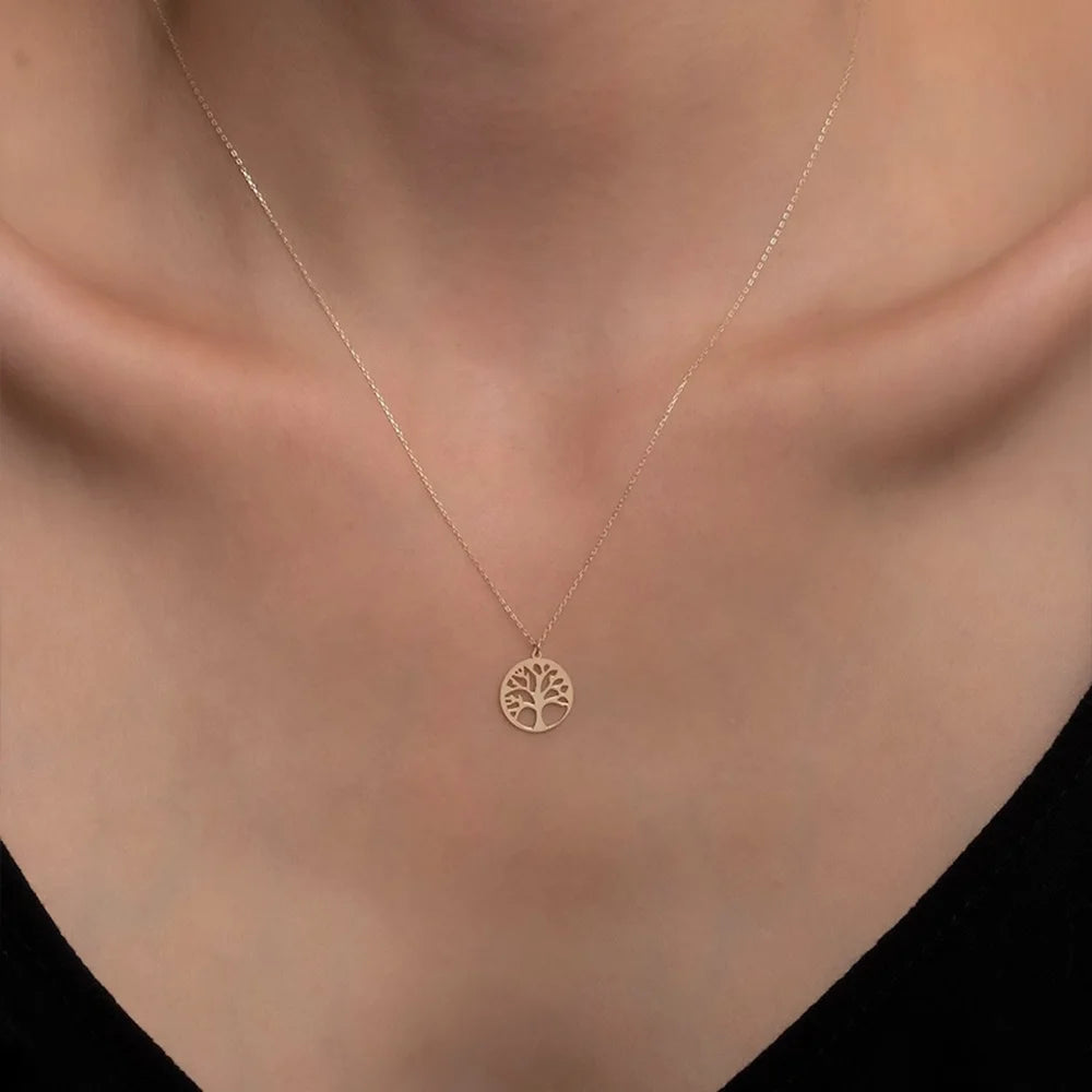 Gold necklace with a tree pendant on a person's neck