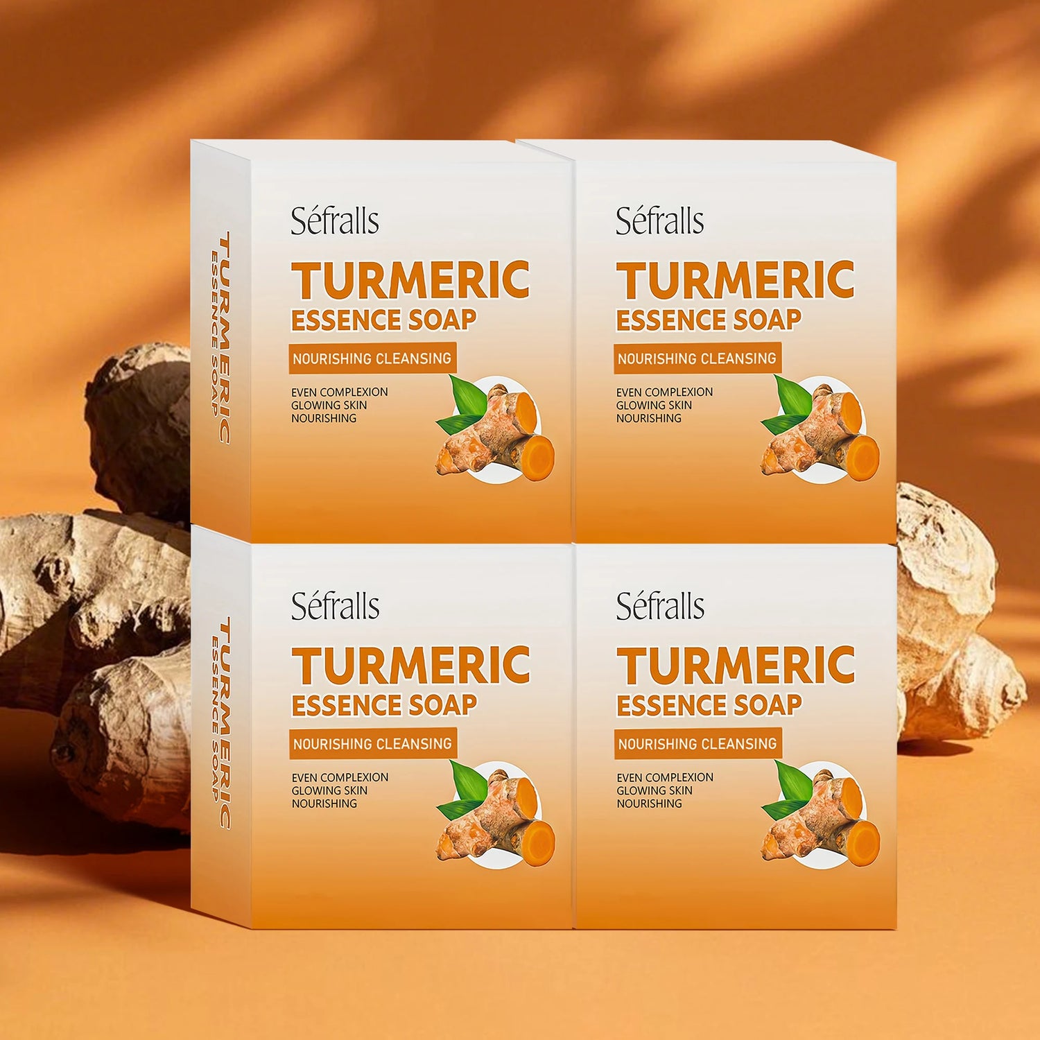 Four boxes of Séfralls Turmeric Essence Soap on an orange background with turmeric roots.